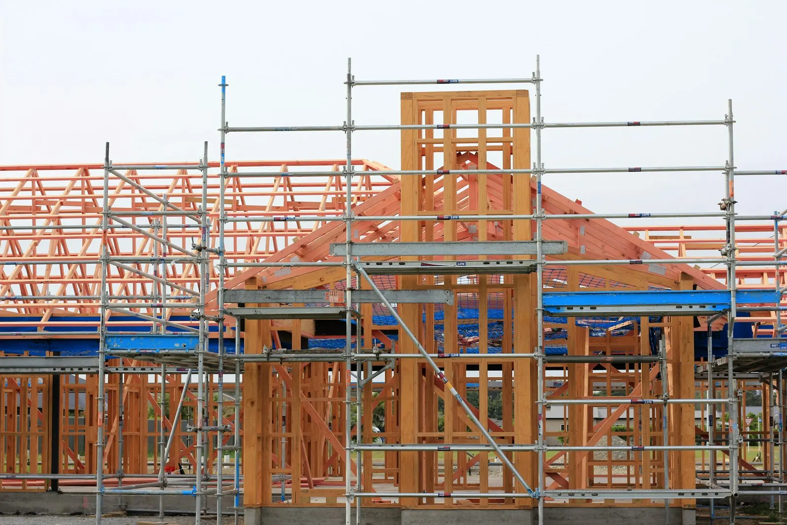 Timber-framed houses under construction behind scaffolding
