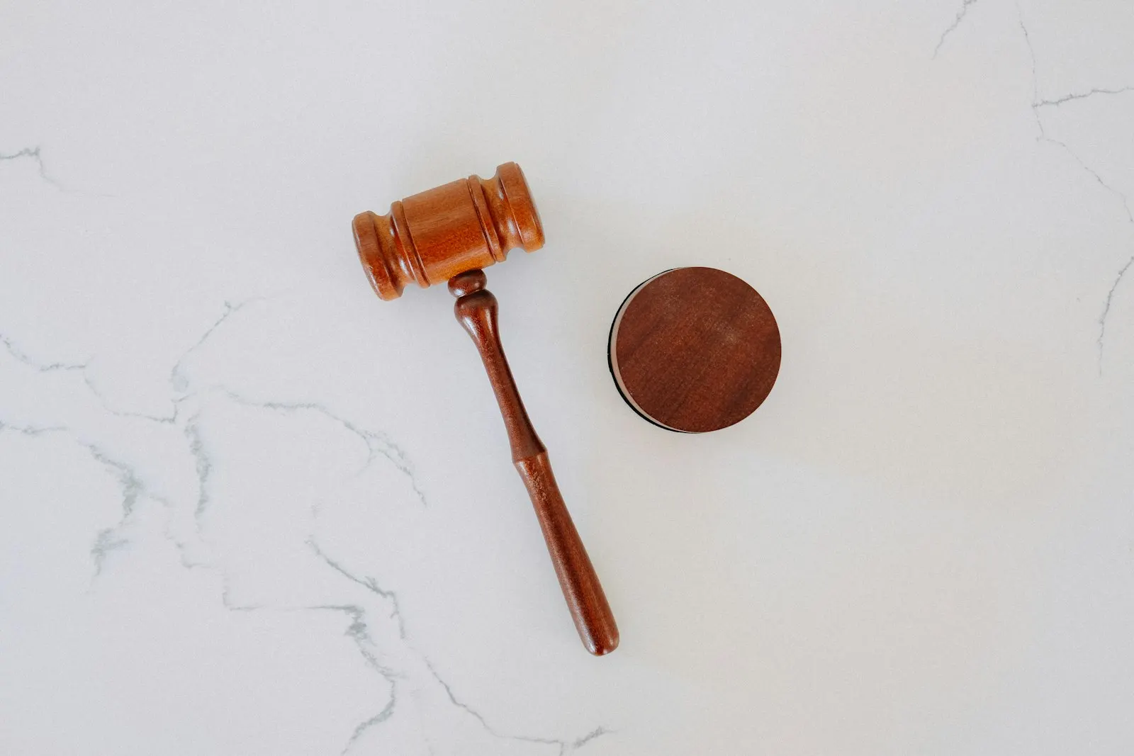 A wooden auction gavel resting beside its block on a marble surface