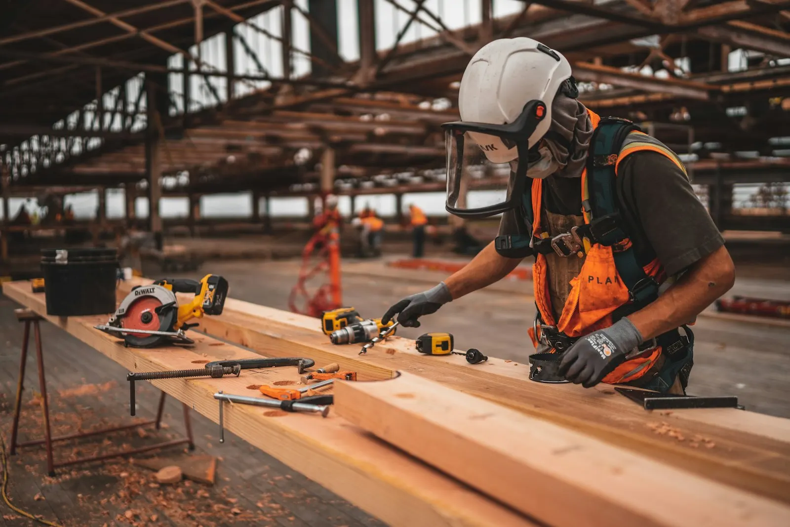 A worker in a helmet and safety gear cutting timber on a building site