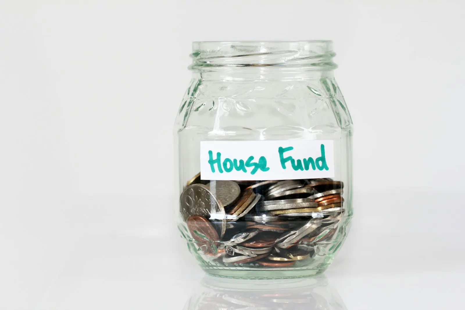 A glass jar labelled House Fund filled with coins