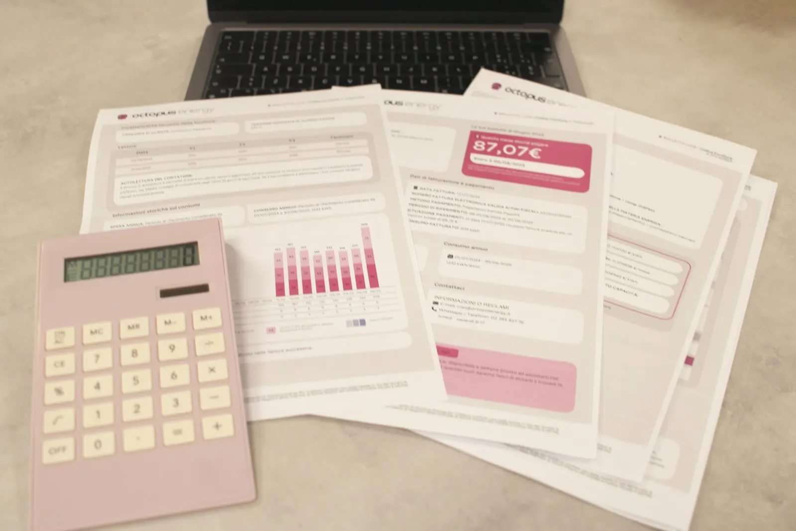 Printed statements and bills spread beside a calculator and a laptop