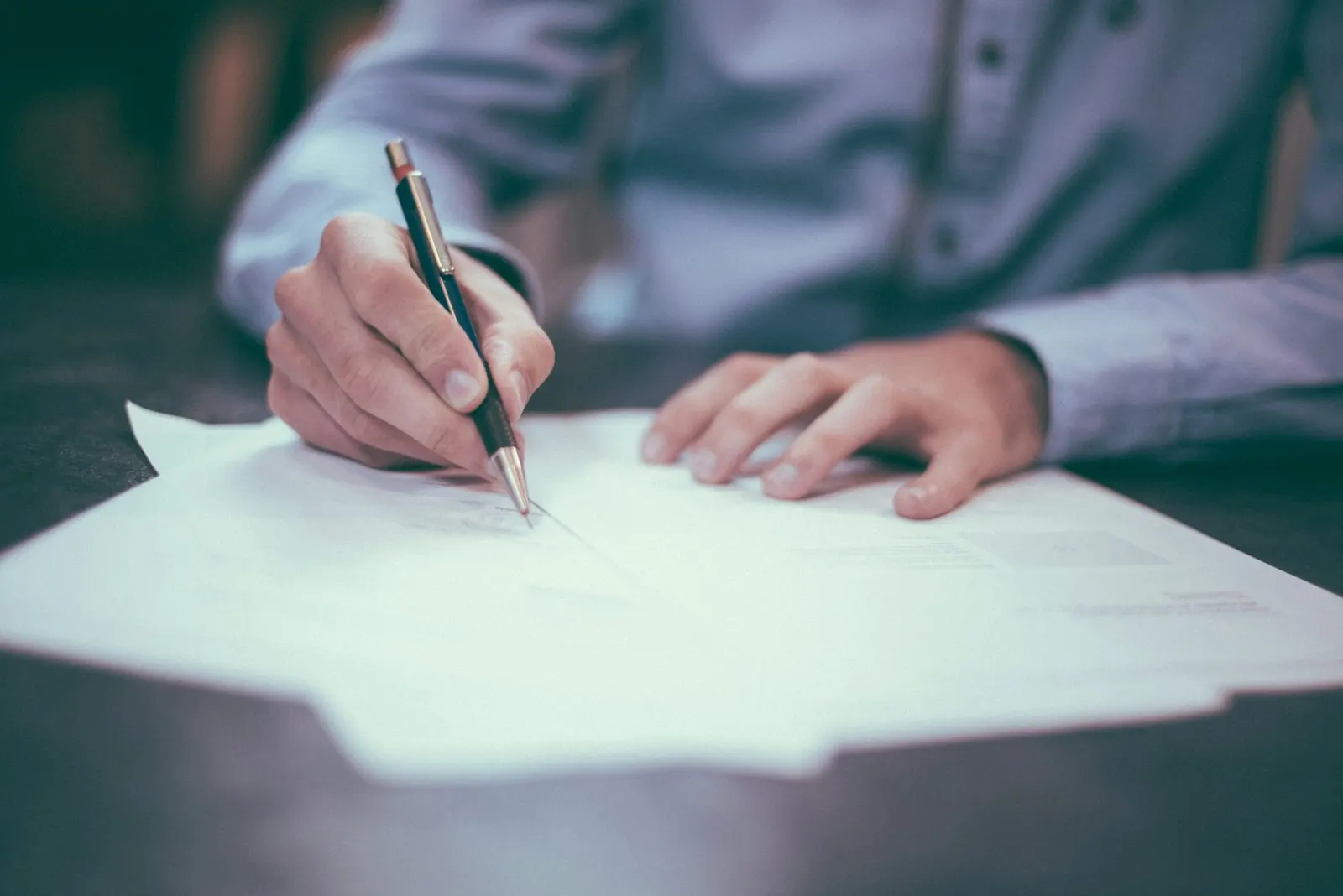A hand writing on a sheet of paper with a pencil